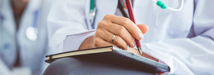 Close-up of a healthcare professional writing in a notebook
