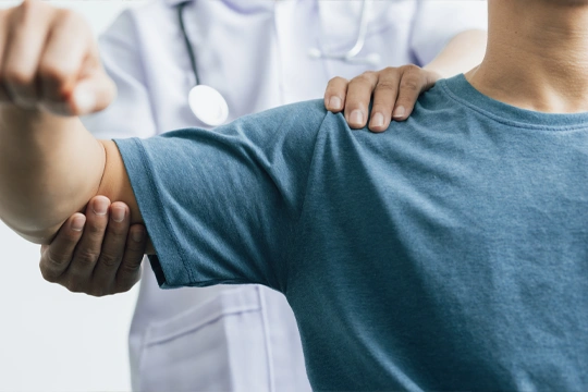 Healthcare professional assisting a person in raising their arm during a physical examination