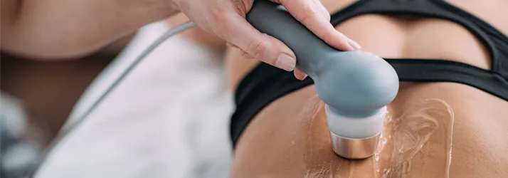 Close up of a tool for therapeutic ultrasound in use on a woman's back.
