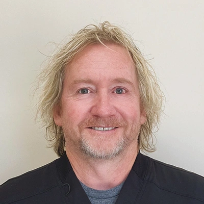 Person with light, wavy, shoulder-length hair wearing a dark top