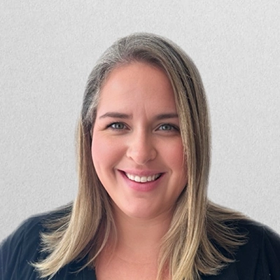 Staff Member Ashley Smiling In Front Of Off-White Wall