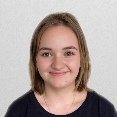 Front Desk Receptionist Autumn Smiling In Front Of Off-White Wall