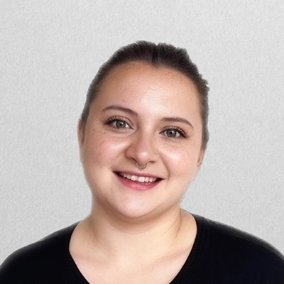 Licensed Massage Therapist Kara Smiling In Front Of Off-White Wall