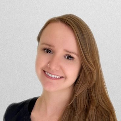 Licensed Massage Therapist Tatiana Smiling In Front Of Off-White Wall