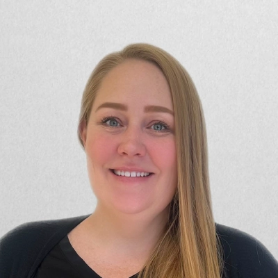 Licensed Massage Therapist Trisha Smiling In Front Of Off-White Wall